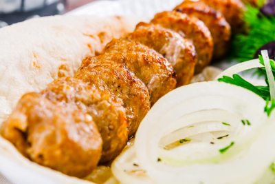 Mutton kebab with onion and herbs on white plate